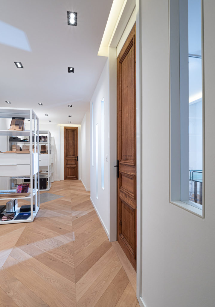 Couloir rénové avec parquet en point de Hongrie et portes anciennes en bois conservées, architecture intérieure Camille Brunot à Genève