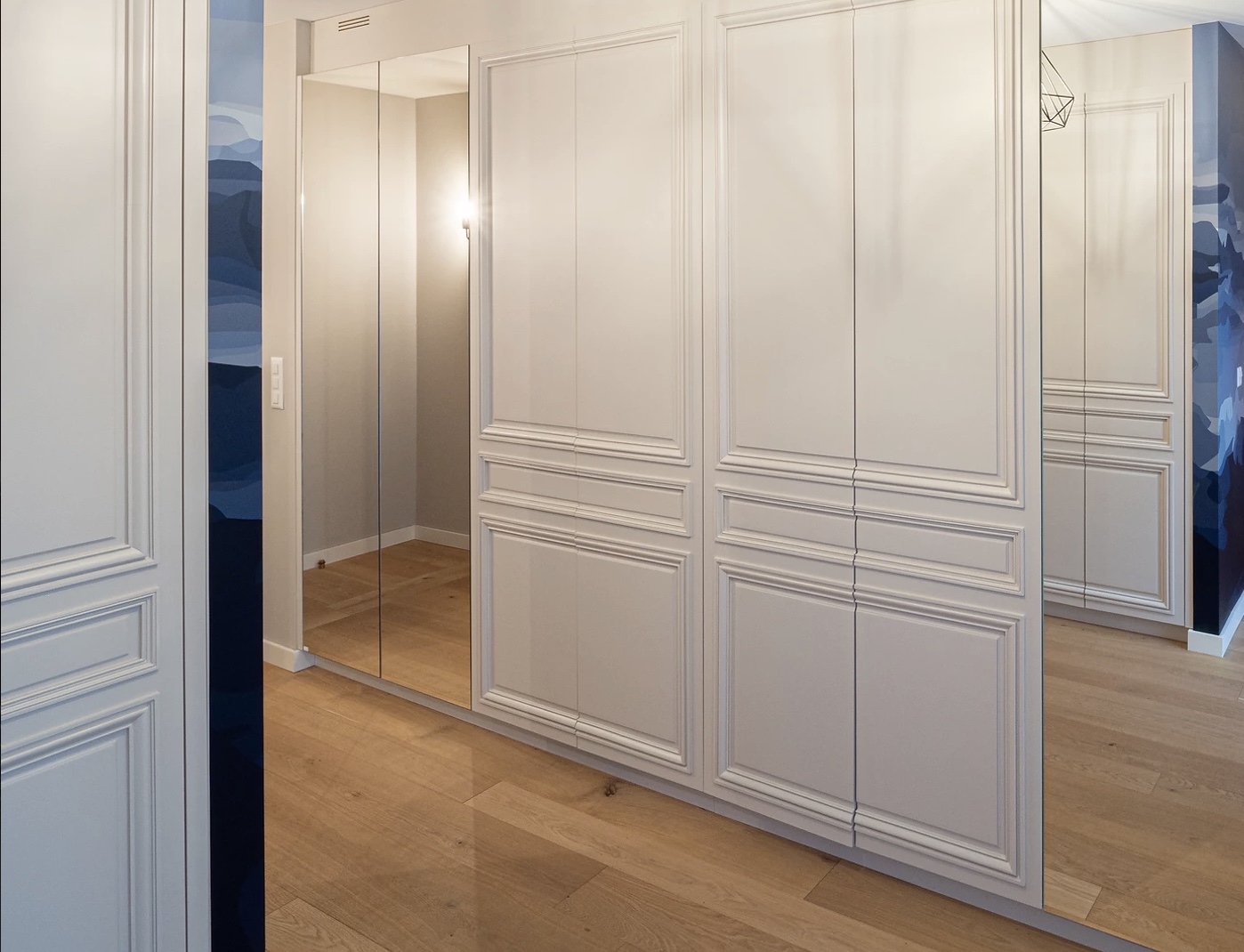 Mobilier sur mesure à Genève : cloison courbe intégrant étagères et niches lumineuses dans l’appartement Bémont, par le studio Camille Brunot