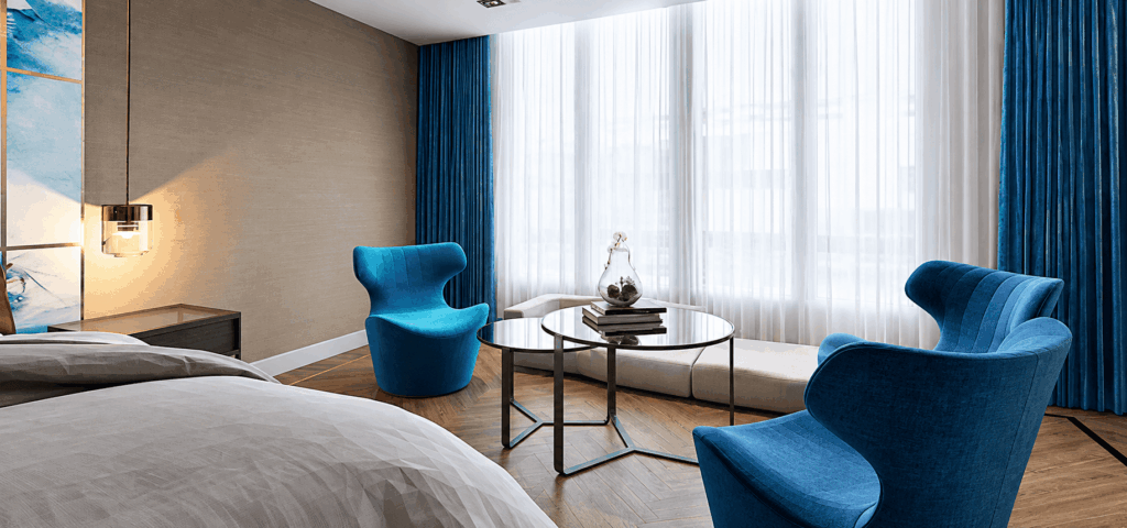 Visualisation 3D d’une chambre avec coin salon, fauteuils bleus, rideaux en velours et voilage, parquet en chevrons, projet Camille Brunot