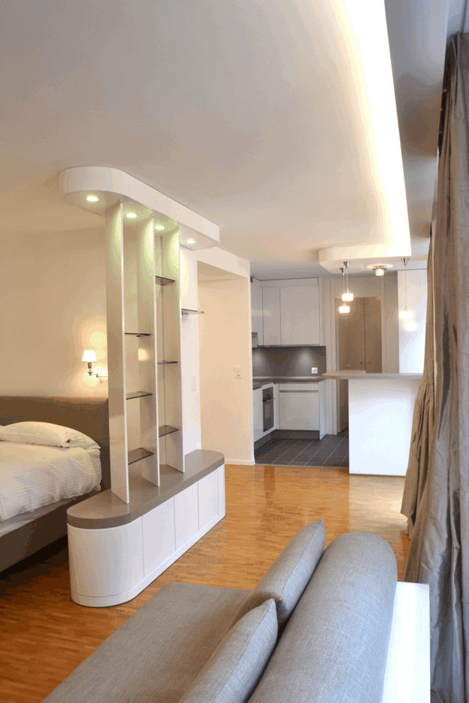 Appartement Bémont à Genève : chambre et séjour séparés par une cloison courbe avec niches éclairées, architecture intérieure Camille Brunot