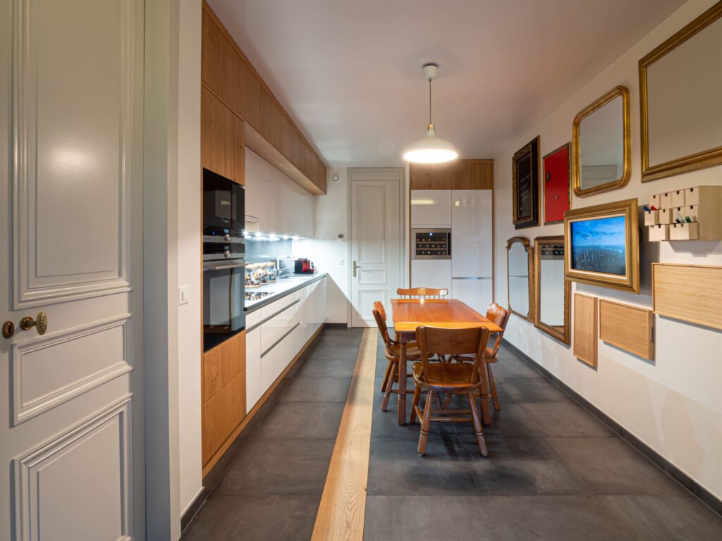 Cuisine sur mesure dans un appartement ancien rénové à Genève, portes à moulures conservées, façades laquées blanches et bois, Camille Brunot