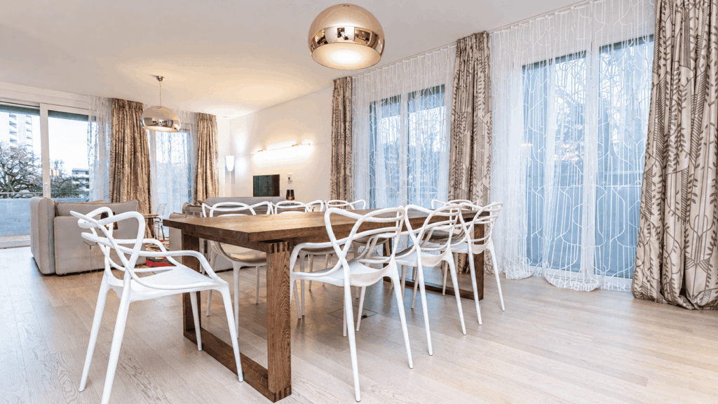 Séjour et salle à manger rénovés à Genève, voilages et rideaux sur mesure, table en bois massif et suspensions cuivrées, Camille Brunot